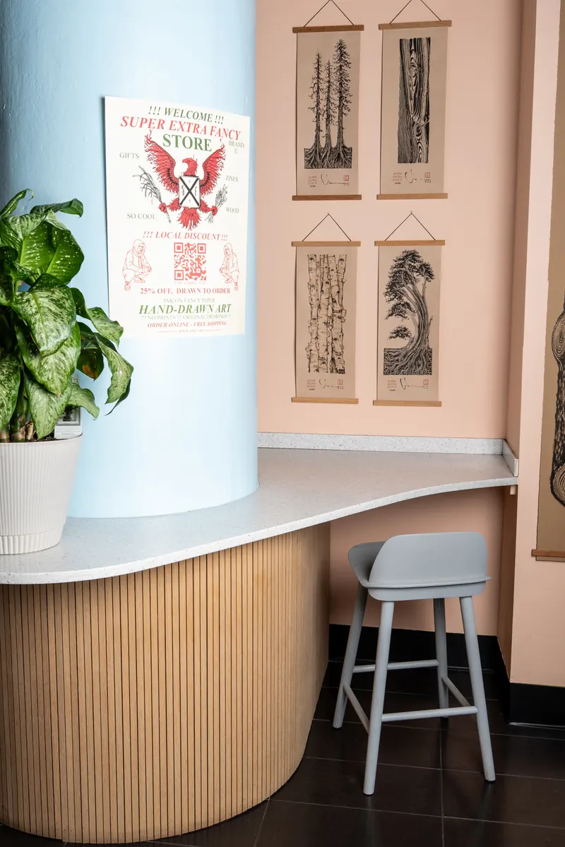 The corner we share with Super Extra Fancy: their welcome poster on a sky-blue column and their hand-drawn prints on the wall, above a terrazzo ledge with a stool