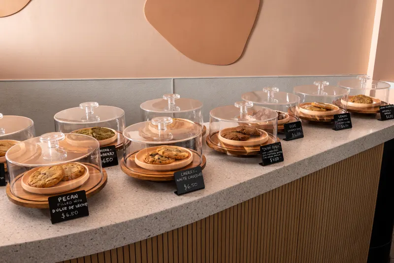 Looking down the counter across the domes — pecan dulce de leche in front, matcha and chocolate chip behind, each with its chalk tag